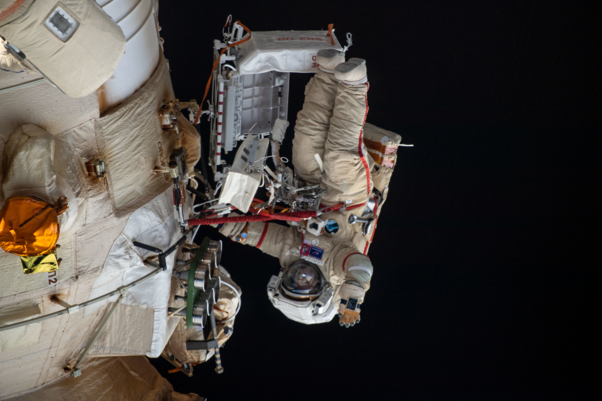 (April 18, 2022) --- Cosmonaut Oleg Artemyev waves to the camera while working outside the Nauka multipurpose laboratory module during a spacewalk that lasted for six hours and 37 minutes to outfit Nauka and configure the European robotic arm on the International Space Station's Russian segment.