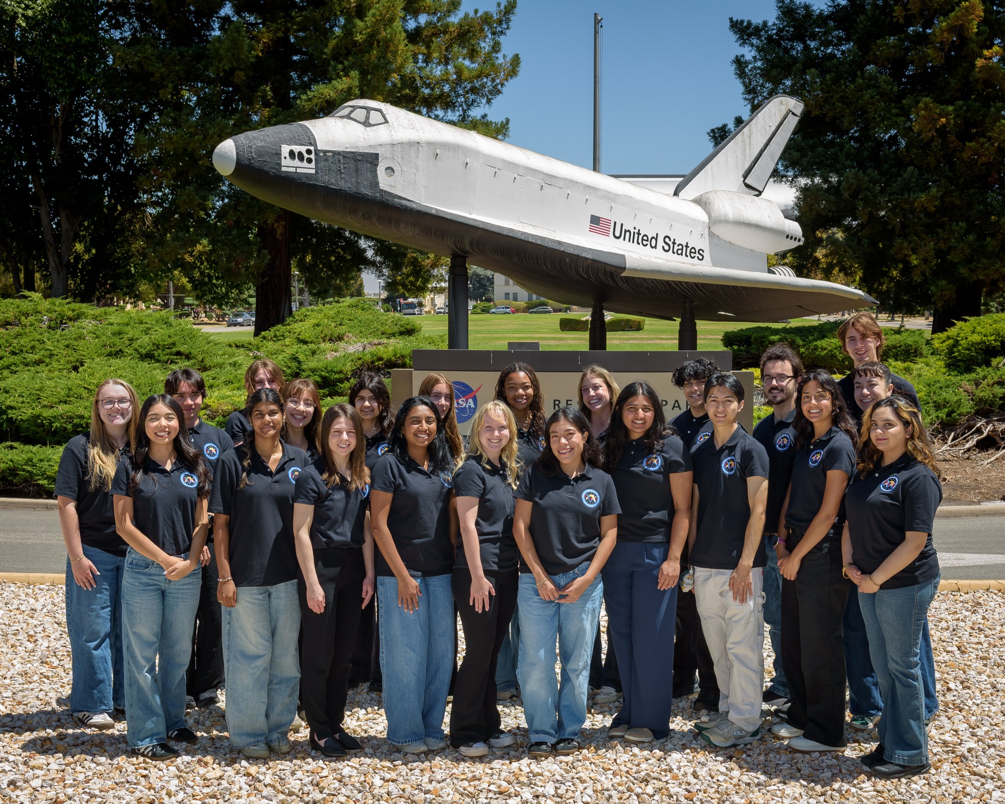 group photo in front a model of a space shuttle