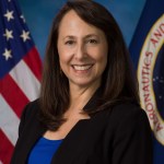 white woman in black suit and blue shirt