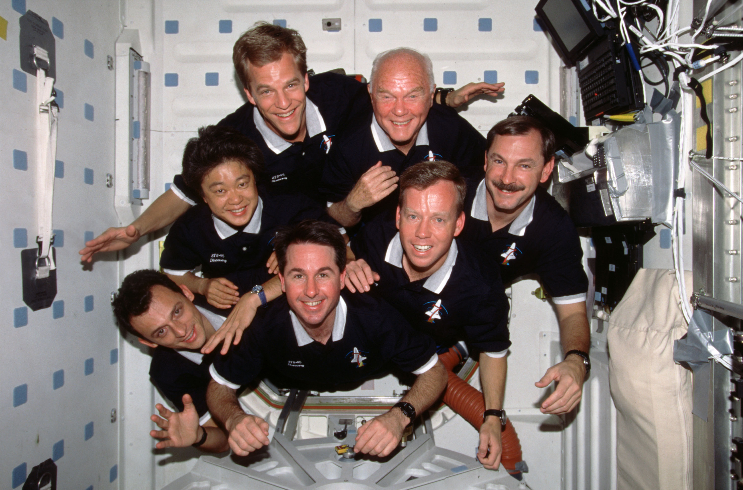 STS-95 astronauts, clockwise from lower left, Pedro F. Duque, Chiaki Mukai, Scott E. Parazynski, John H. Glenn, Curtis L. Brown, Steven W. Lindsey, and Stephen K. Robinson