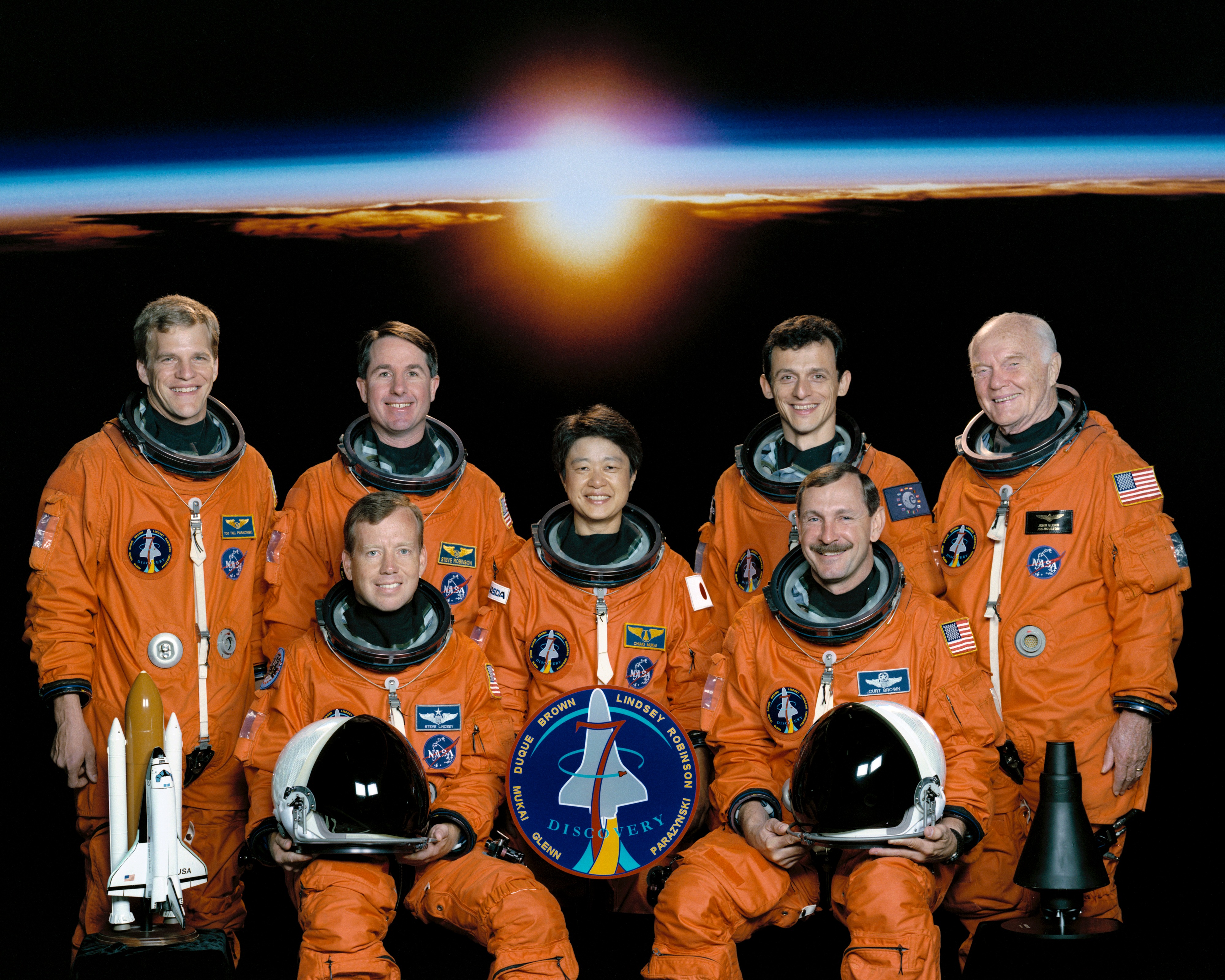 STS-95 astronauts Steven W. Lindsey, seated left, and Curtis L. Brown; Scott E. Parazynski, standing left, Stephen K. Robinson, Chiaki Mukai of the National Space Development Agency of Japan, now the Japan Aerospace Exploration Agency, Pedro F. Duque of the European Space Agency, and John H. Glenn