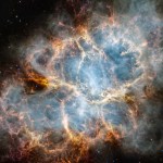 The Crab Nebula. An oval nebula with complex structure against a black background. On the nebula’s exterior, particularly at the top left and bottom left, lie curtains of glowing red and orange fluffy material. Its interior shell shows large-scale loops of mottled filaments of yellow-white and green, studded with clumps and knots. Translucent thin ribbons of smoky white lie within the remnant’s interior, brightest toward its center. The white material follows different directions throughout, including sometimes sharply curving away from certain regions within the remnant. A faint, wispy ring of white material encircles the very center of the nebula. Around and within the supernova remnant are many points of blue, red, and yellow light.