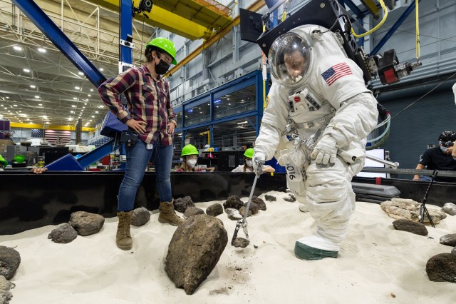 NASA engineer Scott Wray uses tongs to pick up geology samples during testing at NASA's Johnson Space Center.