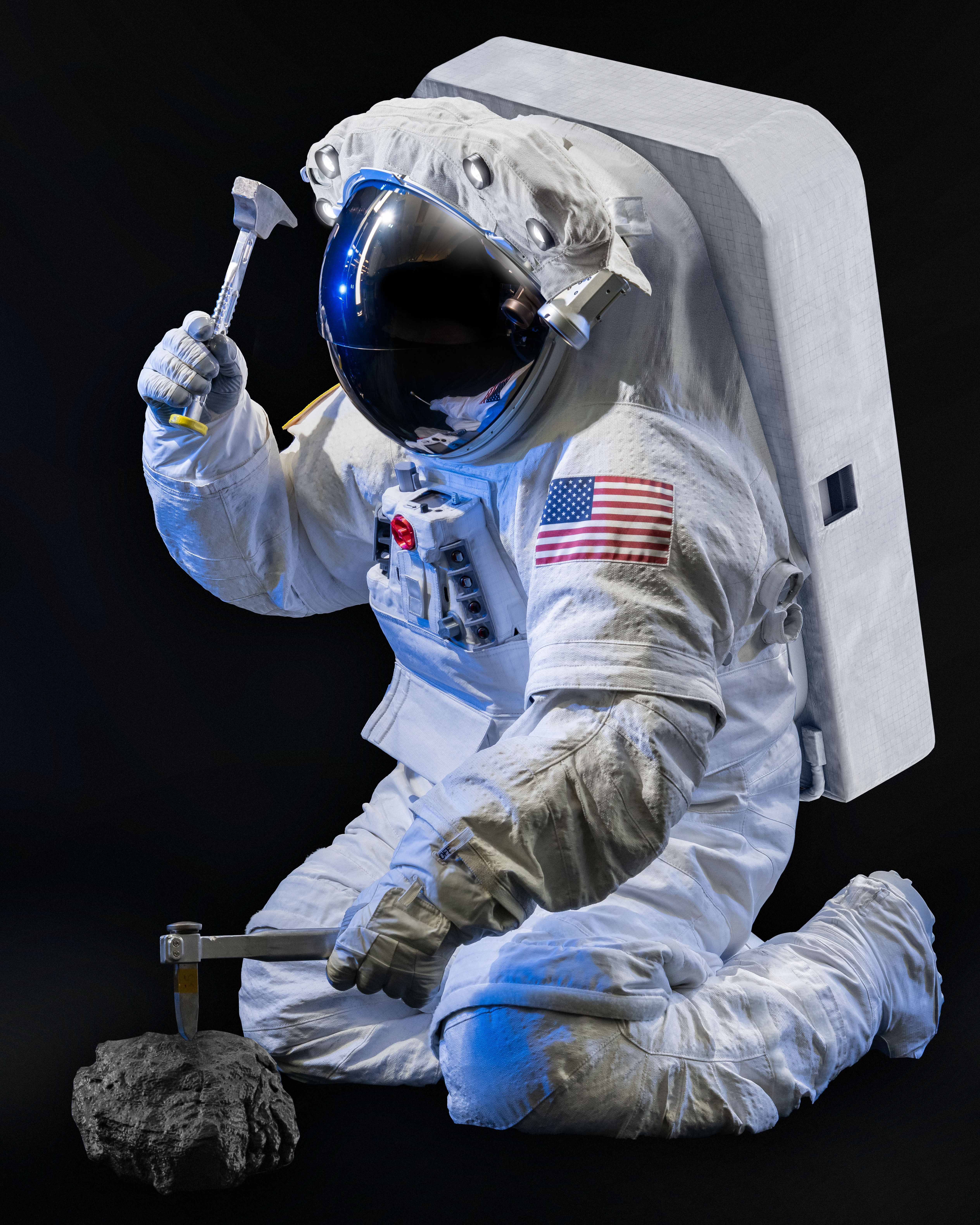 NASA engineer Scott Wray wearing NASA's xEMU (Exploration Extravehicular Mobility Unit) planetary spacesuit prototype while using a hammer and chis...