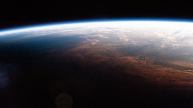 iss070e008937 (Oct. 25, 2023) -- As the International Space Station entered orbital nighttime 260 miles above the Southernmost Point of Alaska, shadows can be seen reaching a wall of clouds colored coral from the Sun.