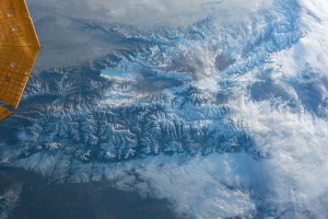 iss070e029759 (Nov. 24, 2023) -- A layer of clouds blends in with snow covering the Tian Shan mountain range in Central Asia as the International Space Station orbited 261 miles above. In the top left corner of the image, the cymbal-shaped solar array of Northrop Grumman's Cygnus spacecraft peeks through.