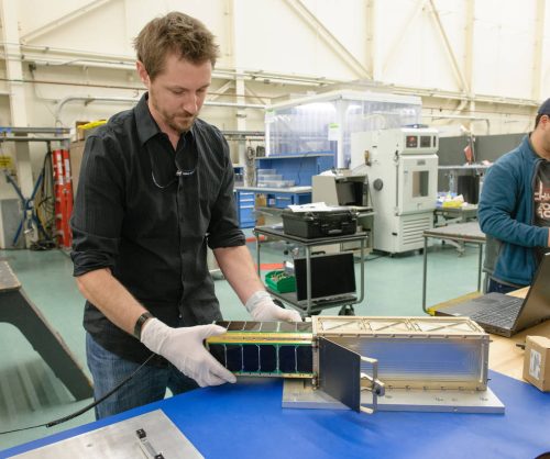 Abraham Rademacher places the fully assembled SporeSat spacecraft