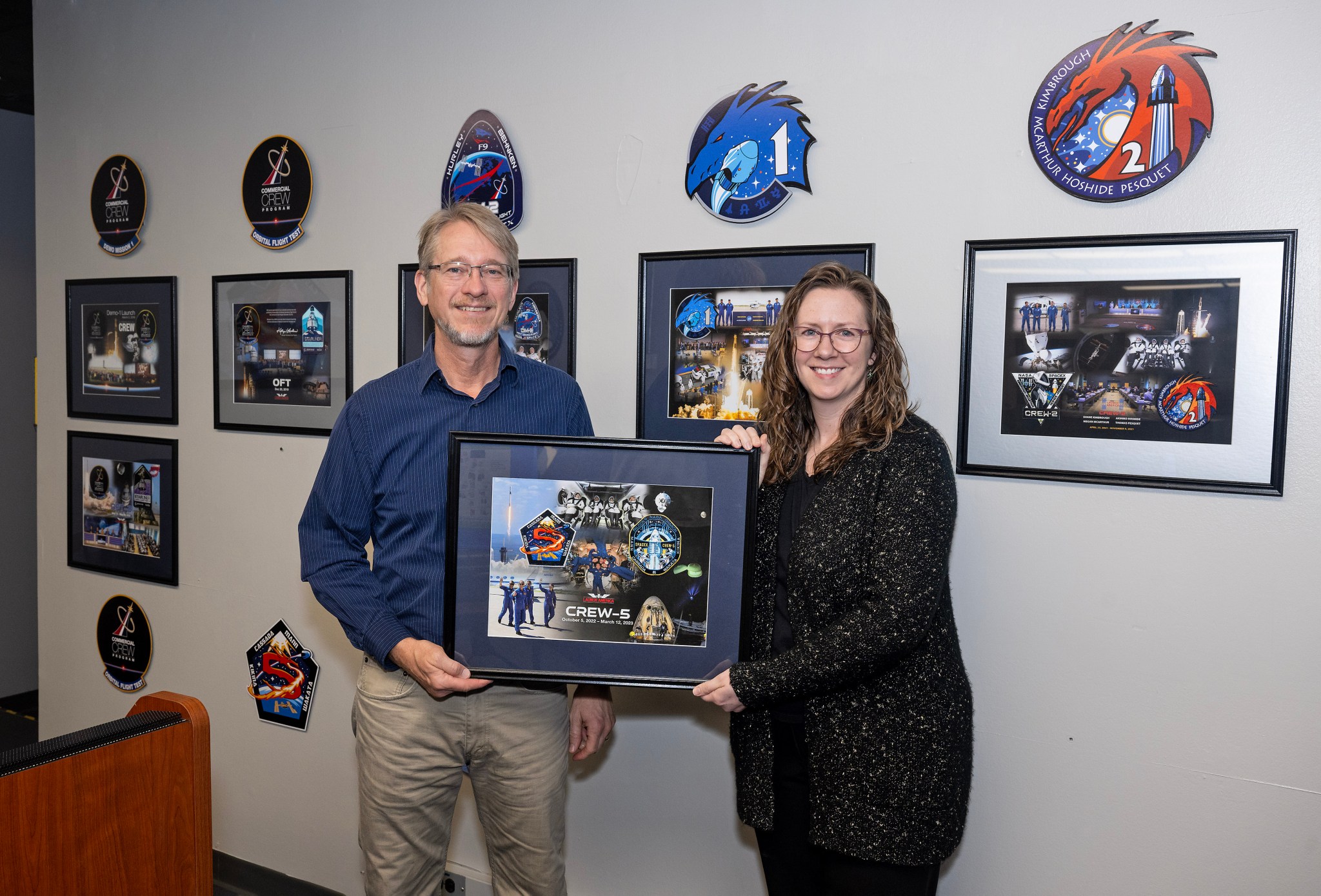 Dave Gwaltney, left, Launch Vehicle Systems Office technical assistant and Lisa McCollum, Marshall’s Commercial Crew Program Launch Vehicle Safety Office deputy manager, hold the Crew-5 mission plaque together as they smile.