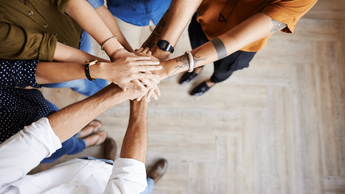 a group of people putting their hands together in a circle