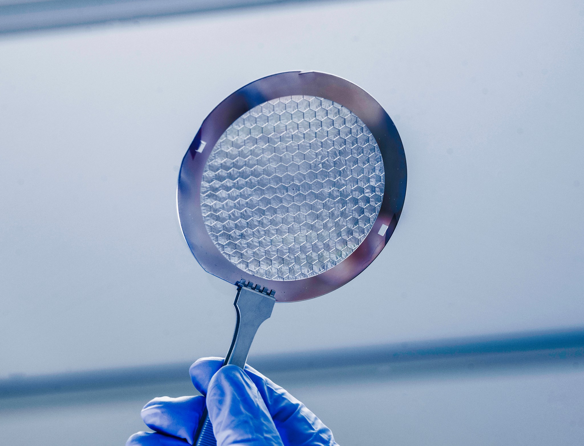an 8-inch wafer of silicon, with hair-thin panels etched with microscopic holes.