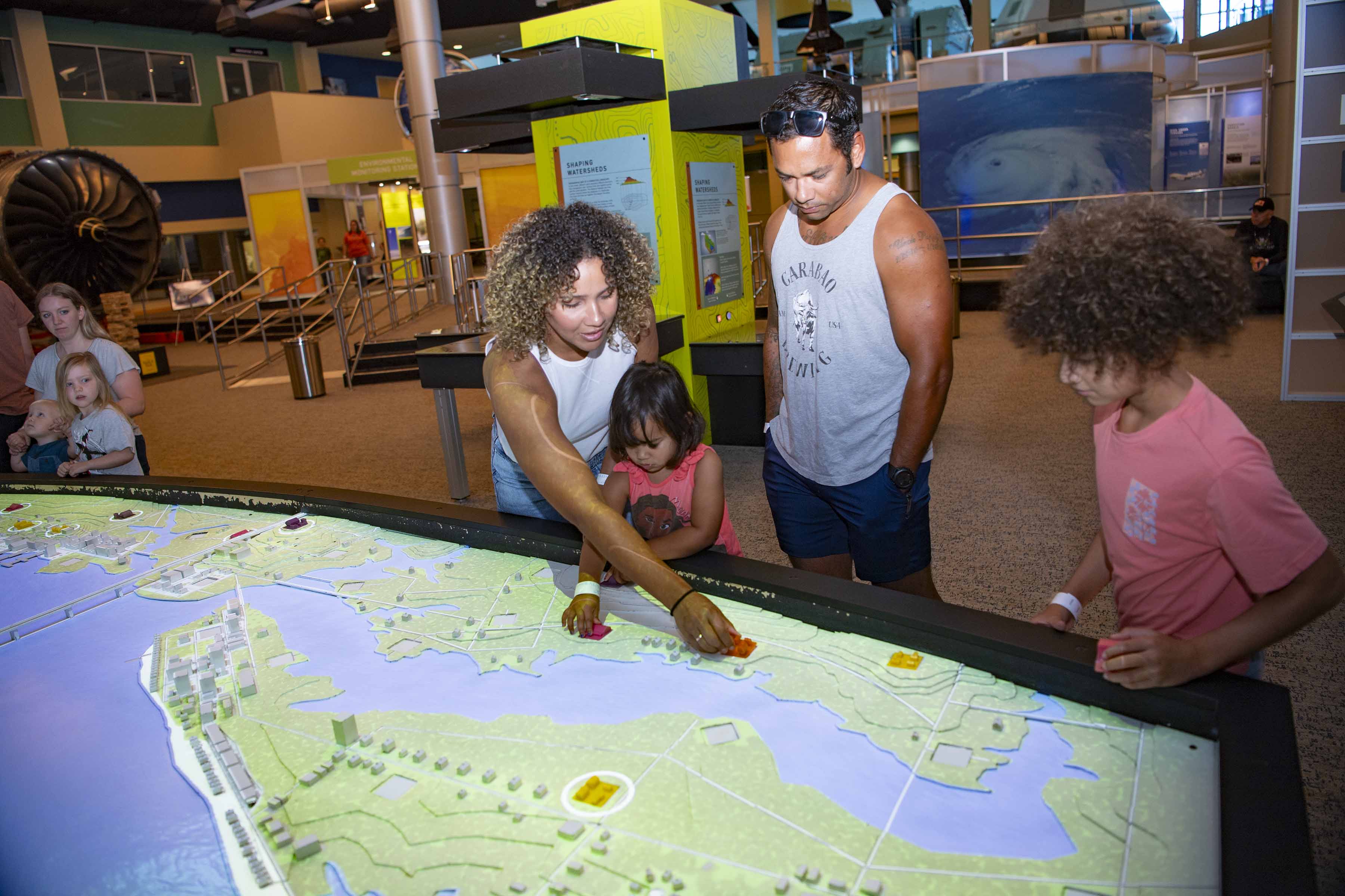 Small group of visitors at INFINITY Science Center interact with the hurricane exhibit.