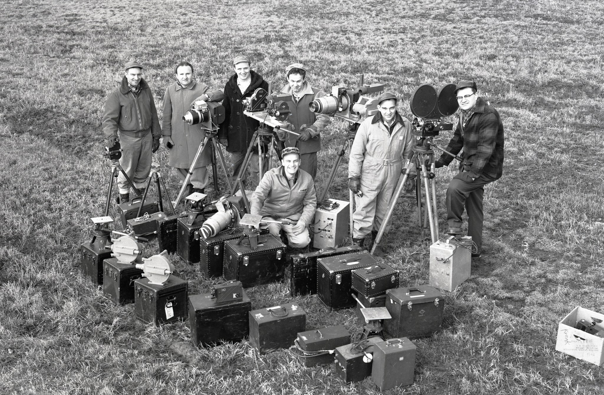 Group of men in field with cameras displayed.