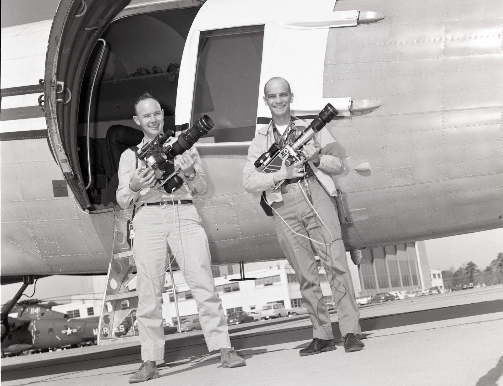 Two men with cameras beside aircraft.