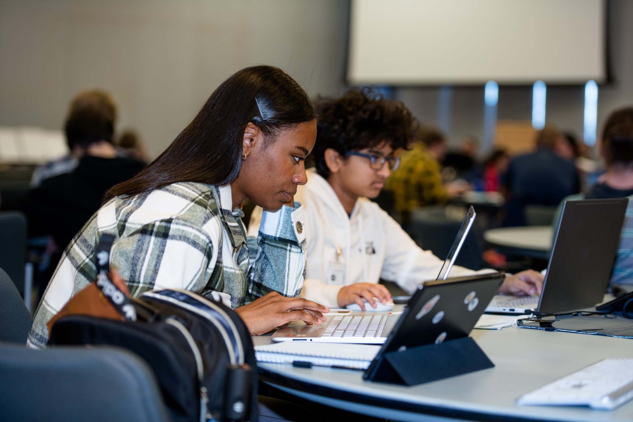 Two participants sit at a table in front of computers.