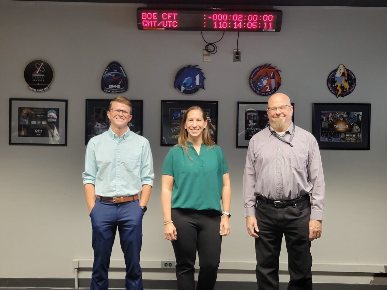 From left, Patrick Mills, liquid propulsion systems engineer, Megan Hines, systems safety engineer, and Ken Schrock, an avionics systems engineer, smile together after hanging their CCP plaques April 20.