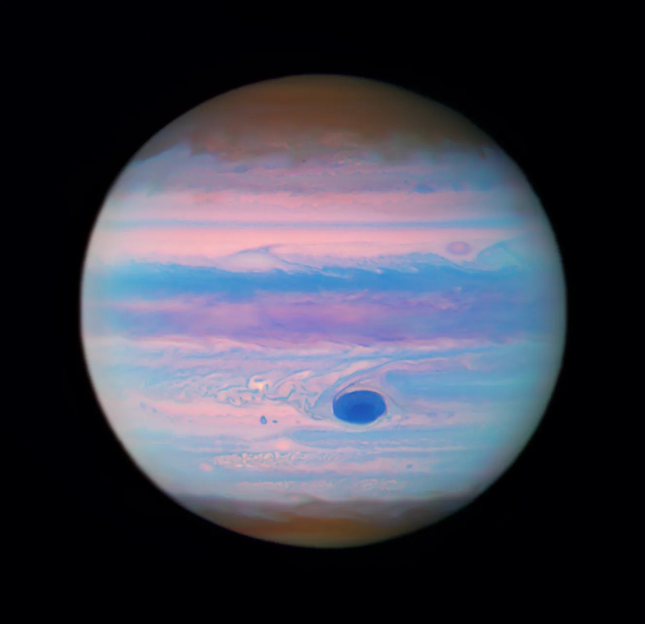 Jupiter looks iridescent in this ultraviolet image from the Hubble Space Telescope. The poles are a muted orange color, while swirls and stripes of pink, orange, blue, and purple cover the rest of the planet. Jupiter's "Great Red Spot" appears a deep blue here.