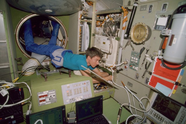 With his feet anchored in a tunnel hatchway, cosmonaut Sergei K. Krikalev, Expedition 1 flight engineer, works in the Zvezda Service Module aboard the International Space Station (ISS). Krikalev is with the Russian Aviation and Space Agency.