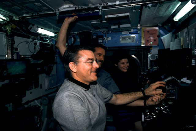 Some of the principal participants of an historical event are pictured in the Destiny laboratory aboard the International Space Station (ISS). In the foreground is astronaut James S. Voss, with astronaut Chris A. Hadfield, STS-100 mission specialist, at center, and astronaut Susan J. Helms in the background. Voss and Helms are Expedition Two flight engineers. A Canadian “handshake in space” occurred at 4:02 p.m (CDT), April 28, 2001, as the Canadian-built space station robotic arm – operated by Helms – transferred its launch cradle over to Endeavour’s robotic arm, with Canadian Space Agency astronaut Hadfield at the controls. In this scene, Hadfield had temporarily vacated his post on Endeavour's aft flight deck and was having a brief strategy meeting with the Expedition Two crew on the docked station. The exchange of the pallet from station arm to shuttle arm marked the first ever robotic-to-robotic transfer in space.