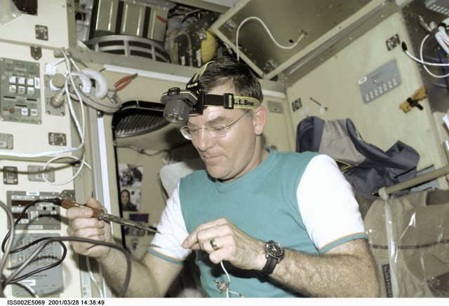 Astronaut James S. Voss, Expedition Two flight engineer, uses a soldering tool for a maintenance task in the Zvezda Service Module onboard the International Space Station (ISS). The image was recorded with a digital still camera.