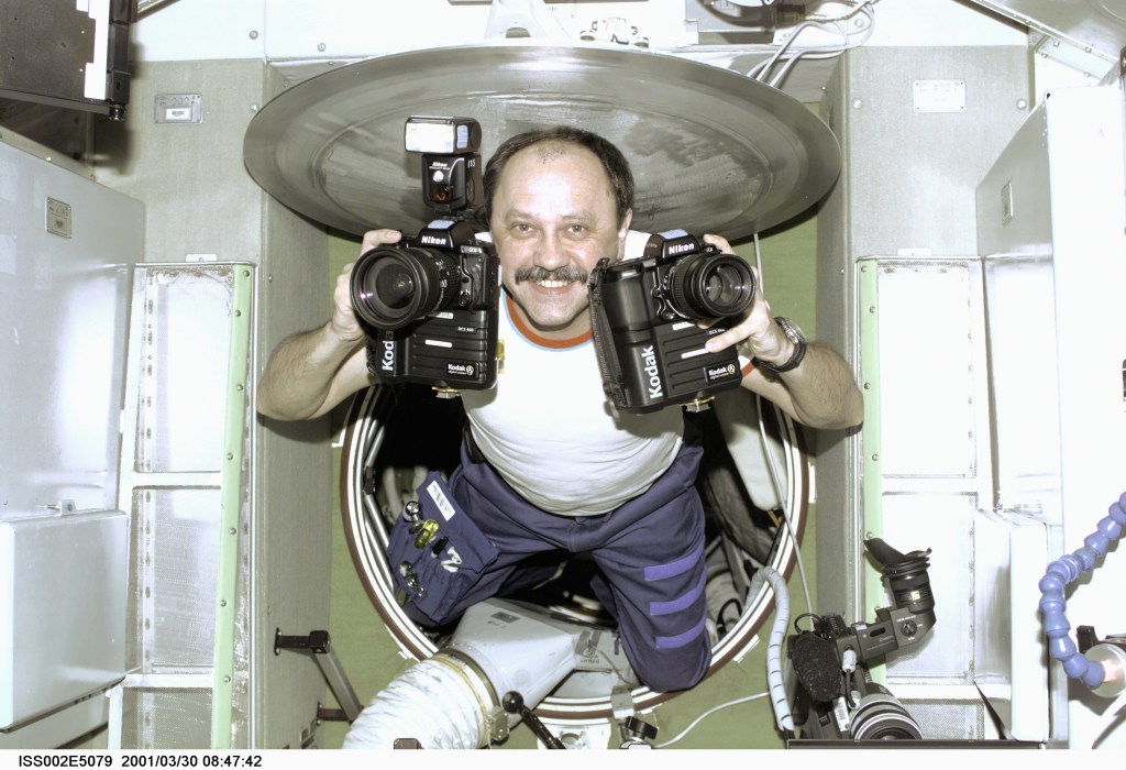 Cosmonaut Yury V. Usachev, Expedition Two commander, floats into the Zvezda Service Module equipped with cameras. Usachev, representing Rosaviakosmos, and two NASA astronauts recently replaced the Expedition One crew onboard the orbital outpost. This image was recorded with a digital still camera.