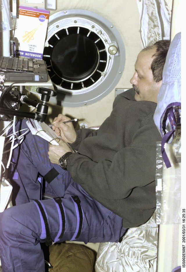 Cosmonaut Yury V. Usachev of Rosaviakosmos, Expedition Two commander, inputs information into a log in the Zvezda Service Module onboard the International Space Station (ISS). Usachev and two American astronauts recently replaced the initial three-member station crew that had been onboard the outpost since early November 2000. The image was taken with a digital still camera.
