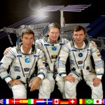 ISS Expedition One Commander William M. (Bill) Shepherd (center) is flanked by Soyuz Commander Yuri P. Gidzenko (right) and Flight Engineer Sergei K. Krikalev (left) in this crew photograph, taken during a break in training in Russia. The three, posed in front of a rendition of the International Space Station, are wearing the Sokol space suits like those they will don for their Soyuz-provided trip to ISS later this month. National flags representing all the international partners run along the bottom of the portrait.