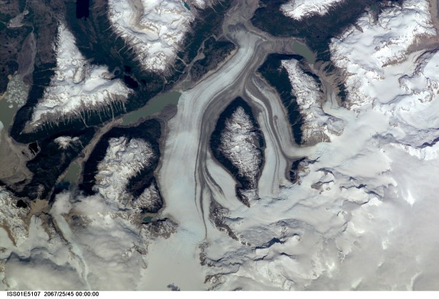 This nadir view of a Chilean glaciated area was provided by one of the early December digital still camera images down linked from the International Space Station (ISS) to ground controllers in Houston. The remote headwaters of the Rio de la Colonia are located on the eastern flank of the Cerro Pared Norte, a high, coastal range of the Andes in southern Chile. This is but a portion of a larger glaciated region of the Chilean coast located at only 47 degrees south latitude. The river actually begins its flow just off the top of this scene at the foot of the two large, converging, valley glaciers near the center. Some of the numerous lakes visible are tinted by the fine glacial sediments suspended in their waters. Note the shards of ice that have calved from the glaciers into the lakes on the left. Also note the shadows of the crest of the over 14,000-foot mountains (lower center). The remote headwaters of the Rio de la Colonia are located on the eastern flank of the Cerro Pared Norte, a high, coastal range of the Andes in southern Chile. This is a but a portion of a larger glaciated region of the Chilean coast located at only 47 degrees south latitude. The river actually begins its flow just off the top of this scene at the foot of the two large, converging, valley glaciers near the center. Some of the numerous lakes visible are tinted by the fine glacial sediments suspended in their waters. Note the shards of ice that have calved from the glaciers into the lakes on the left. Also note the shadows of the crest of the over 14,000-foot mountains (lower center).