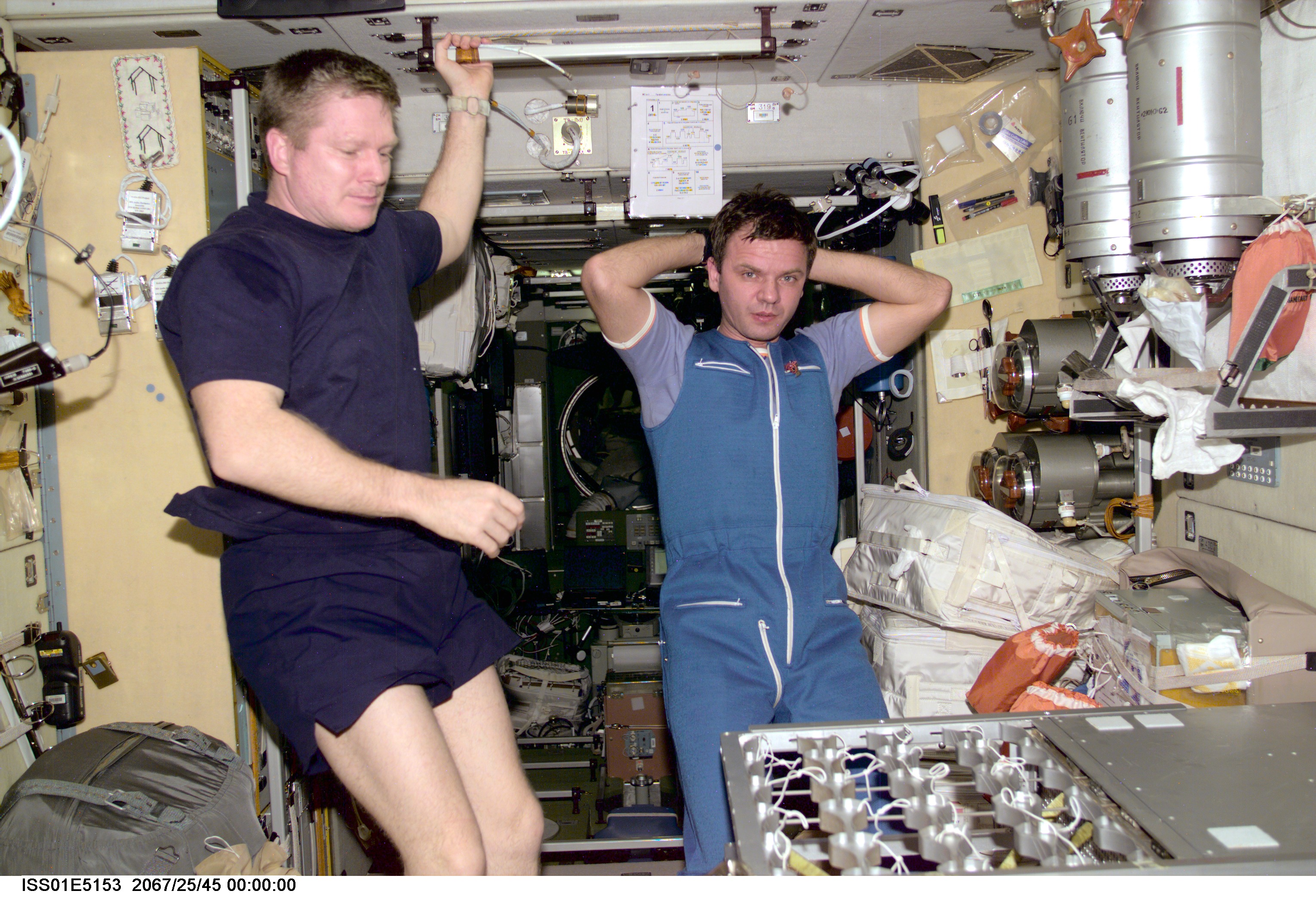Astronaut William M. Shepherd, Expedition 1 commander, and cosmonaut Yuri P. Gidzenko, Soyuz commander, contemplate work they're doing on the food warmer for the Ward Room table aboard the International Space Station's Zvezda Service Module.