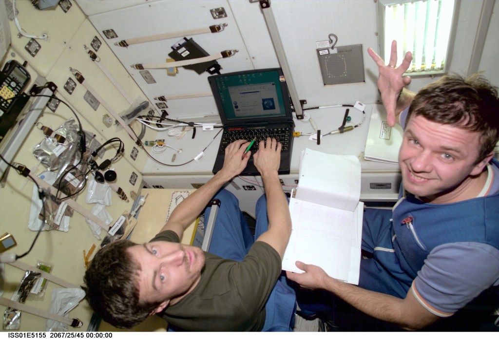 Cosmonauts Sergei K. Krikalev (left), Expedition 1 flight engineer, and Yuri P. Gidzenko, Soyuz commander, input data into a laptop computer in the Zvezda Service Module aboard the Earth-orbiting International Space Station (ISS).