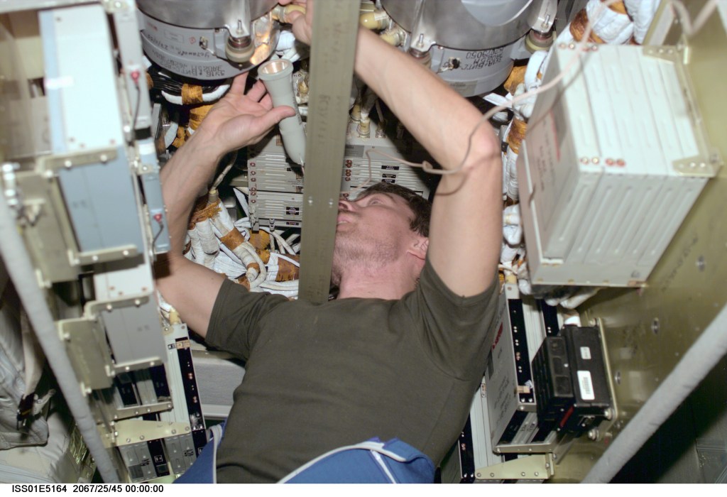 Inside the International Space Station's Zvezda Service Module, cosmonaut Sergei K. Krikalev, Expedition 1 flight engineer, uses a flashlight to check connections on a memory device in the telemetry system for the station.