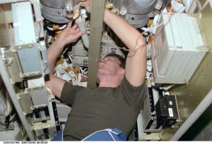 Inside the International Space Station's Zvezda Service Module, cosmonaut Sergei K. Krikalev, Expedition 1 flight engineer, uses a flashlight to check connections on a memory device in the telemetry system for the station.
