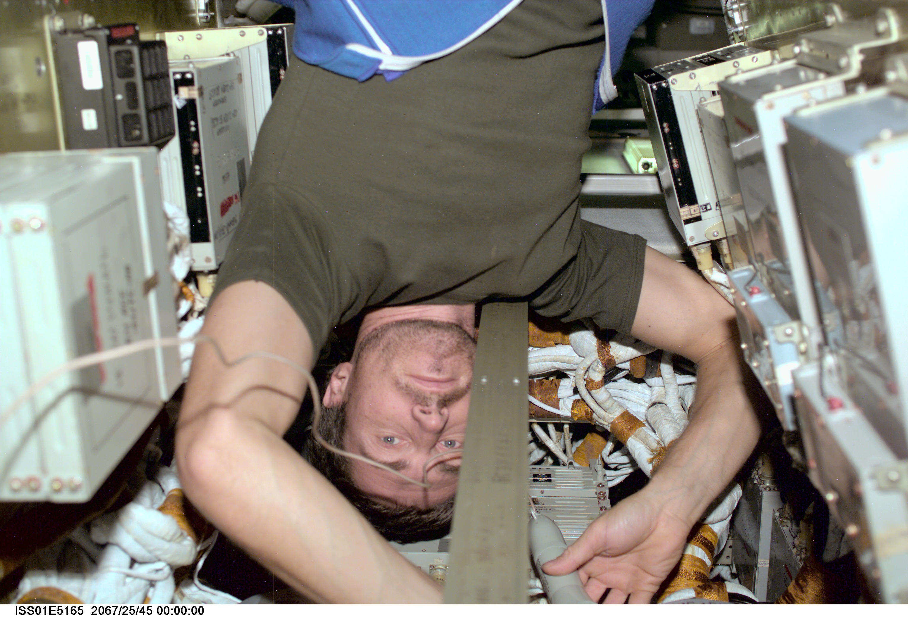 Inside the International Space Station's Zvezda Service Module, cosmonaut Sergei K. Krikalev, Expedition 1 flight engineer, uses a flashlight to check connections on a memory device in the telemetry system for the station.
