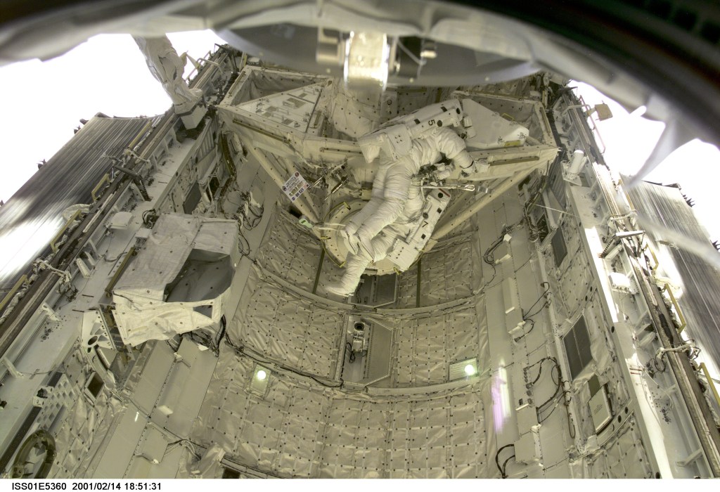 Astronauts Thomas D. Jones (partially obscured) and Robert L. Curbeam, STS-98 mission specialists, are pictured in the cargo bay of the Space Shuttle Atlantis during their third space walk, as photographed with a digital still camera from the International Space Station's new Destiny laboratory.