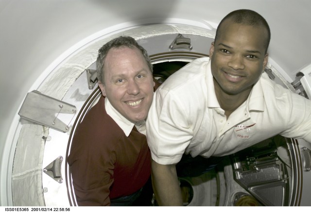 Astronauts Thomas D. Jones (left) and Robert L. Curbeam, STS-98 mission specialists who will accomplish three lengthy space walks during the STS-98/5a mission, share space in a small hatch during break time. The scene was recorded with a digital still camera.