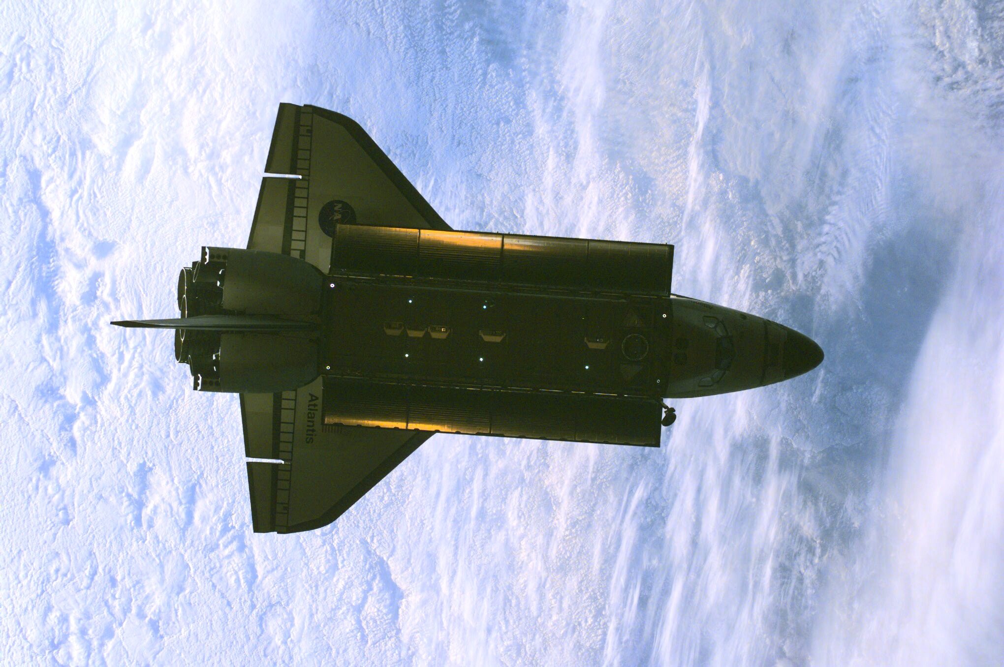 The Space Shuttle Atlantis was photographed by the three-man Expedition One crew aboard the International Space Station (ISS) shortly after the shuttle and the outpost unlinked following several days of joint operations of the two crews. The scene, backdropped against a mass of white clouds on Earth, was recorded with a digital still camera.