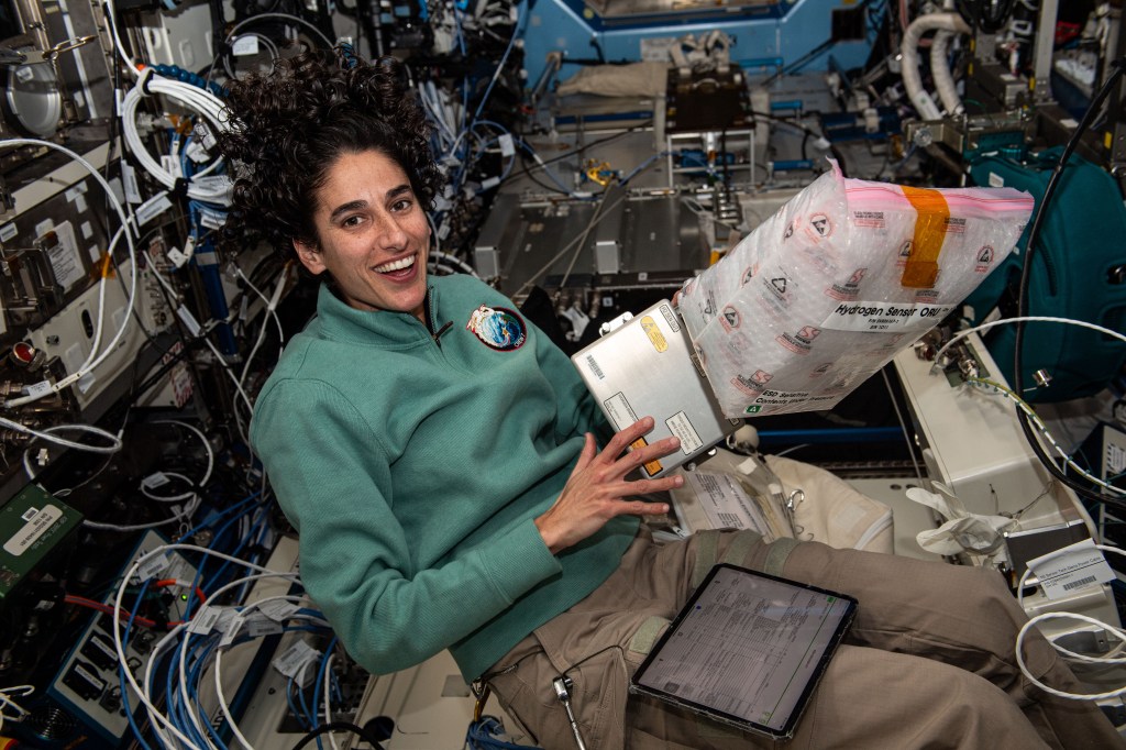 NASA astronaut and Expedition 70 Flight Engineer Jasmin Moghbeli smiles for portrait while installing a new hydrogen sensor on an oxygen generator located inside the International Space Station's Destiny laboratory module.