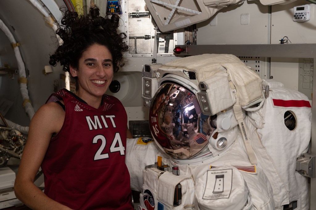 NASA astronaut and Expedition 70 Flight Engineer Jasmin Moghbeli poses with a spacesuit in the International Space Station's Quest airlock.