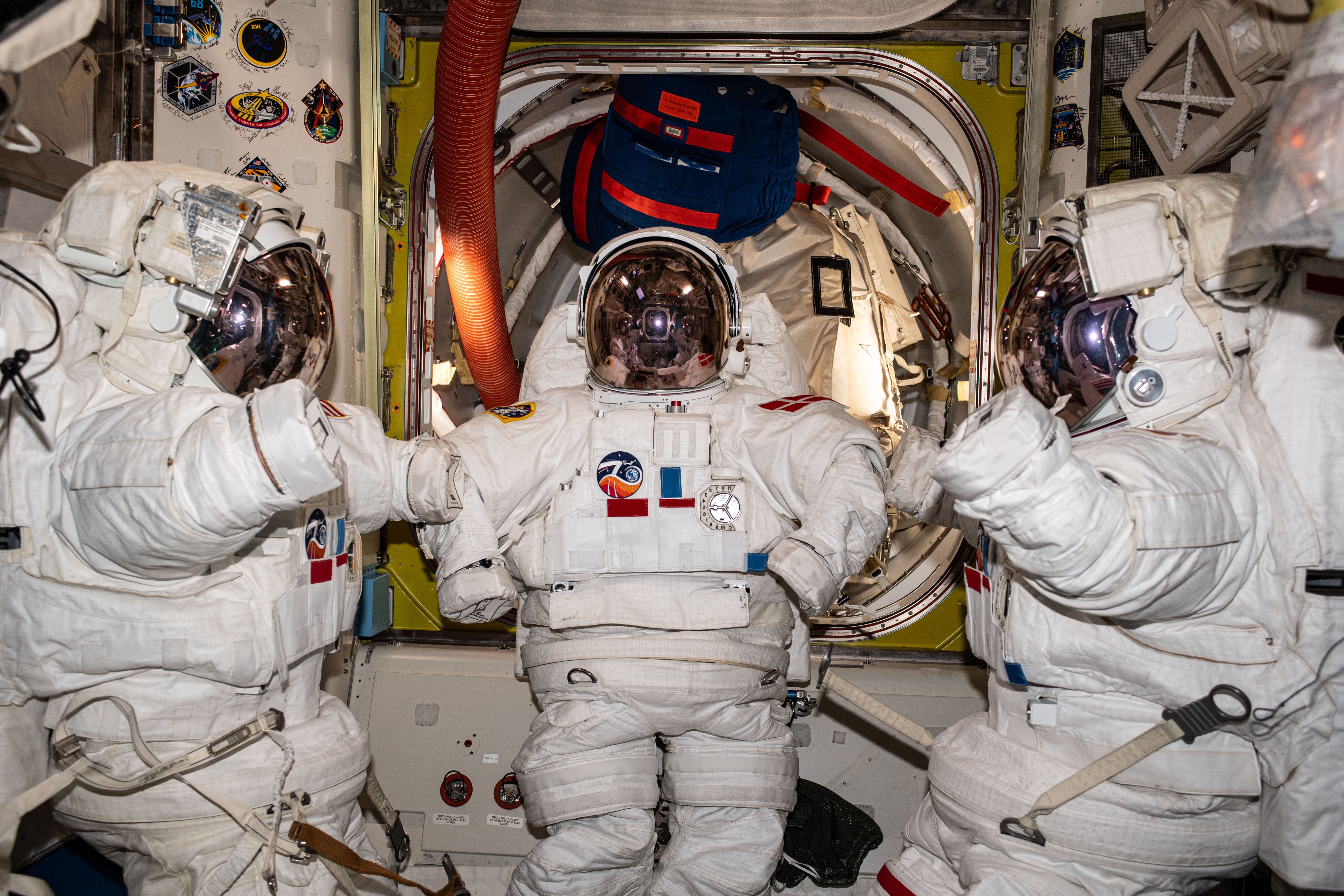 Three near-assembled spacesuits, with their gloves unattached, are pictured inside the International Space Station's Quest airlock ahead of an upcoming spacewalk.