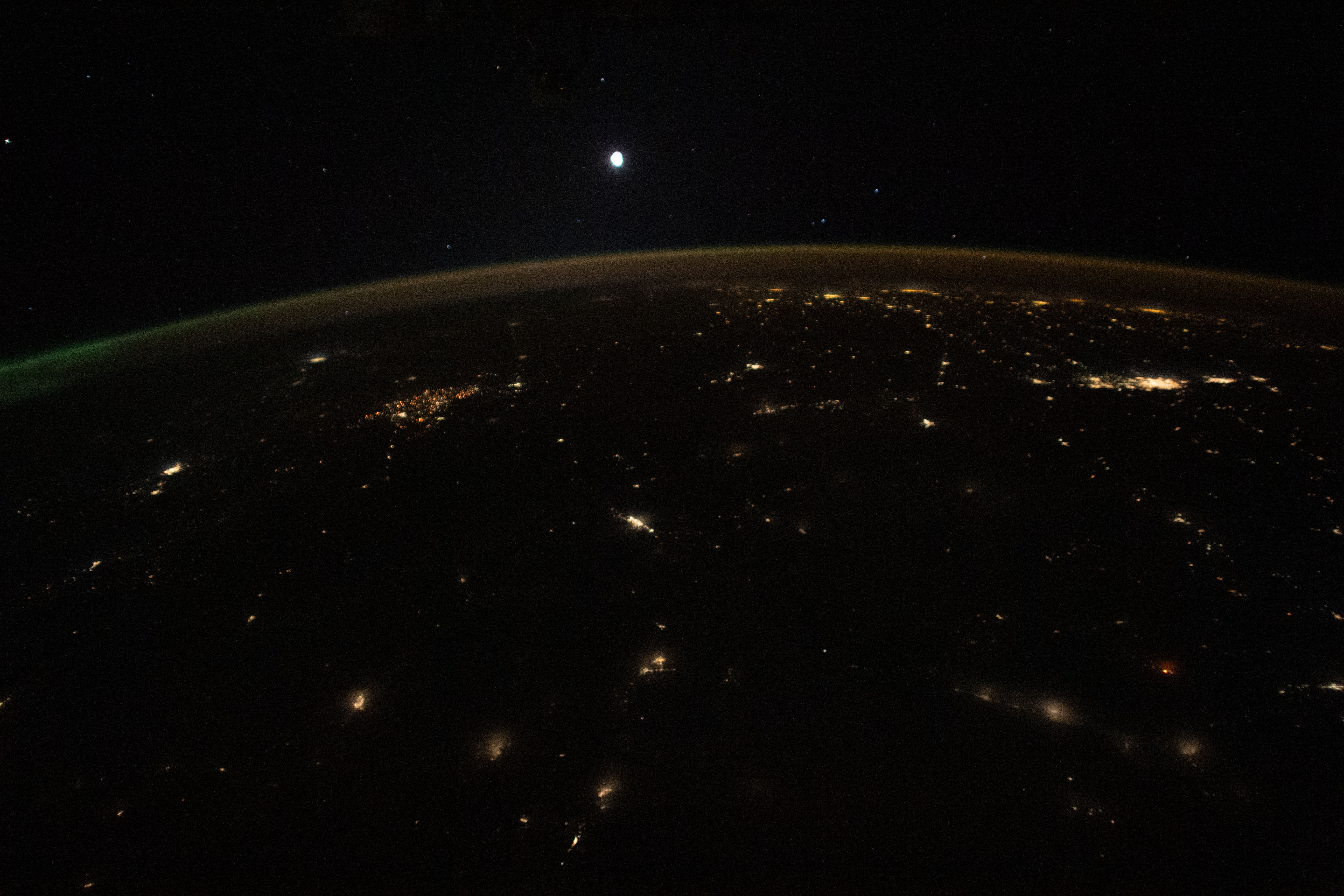 The Moon is pictured above Earth's horizon, its airglow, and an aurora (at far right) in this photograph from the International Space Station as it orbited 261 miles above the northwestern United States.
