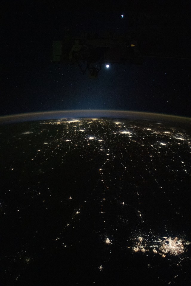 Earth's airglow outlines the planet's horizon with the Moon above in this photograph from the International Space Station as it orbited 260 miles above the midwestern United States. At lower right, the city lights of Denver. Colorado, and its suburbs shine, including the city lights all the way to Chicago, Illinois (at top), and surrounding metropolitan areas.