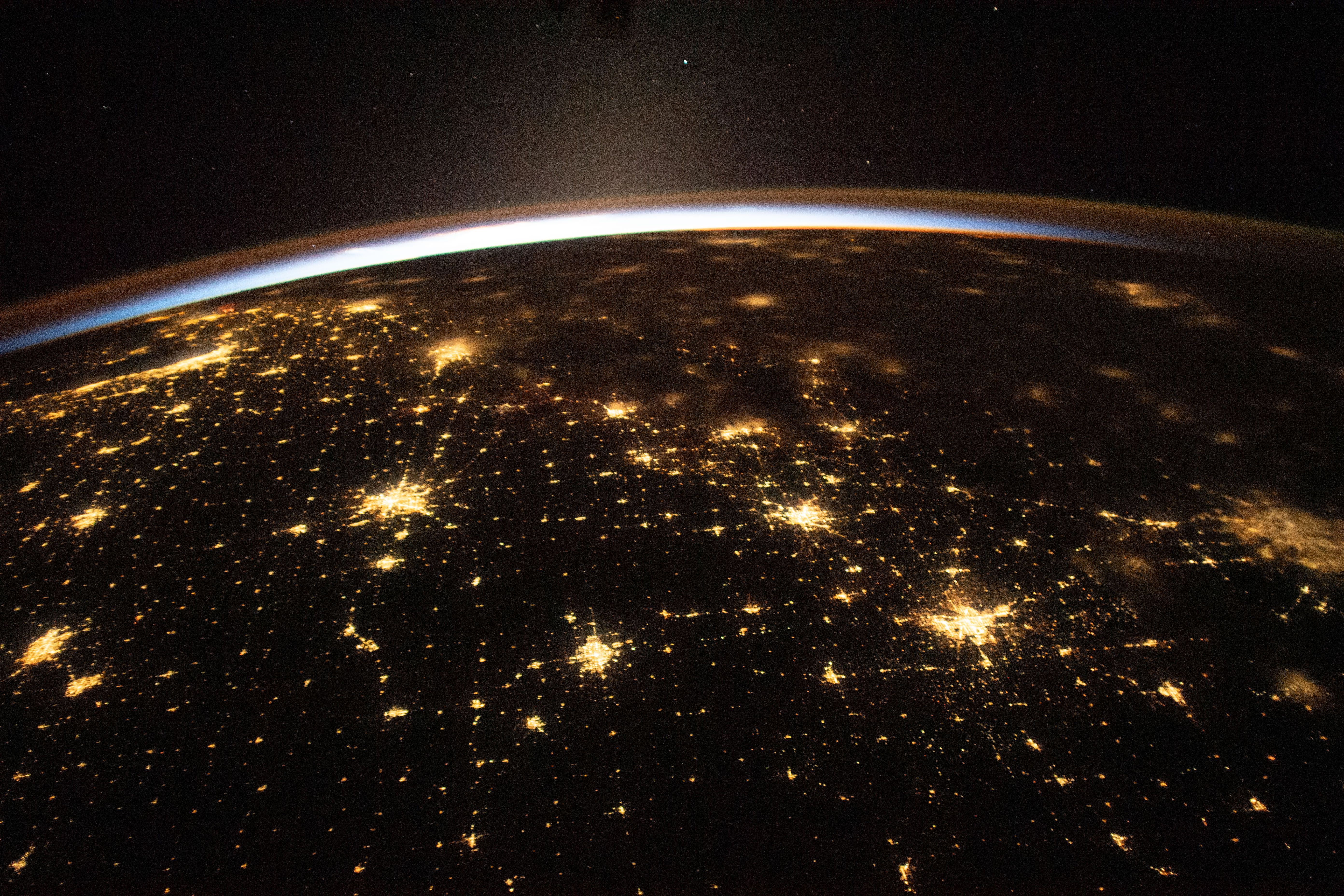 The sun's first rays begin illuminating Earth's atmosphere in this photograph from the International Space Station as it orbited 260 miles above the central United States. At far left, the city lights of Chicago, Illinois, are outlined by Lake Michigan. At far right, the city lights of the Dallas/Forth Worth metropolitan area shine through the clouds.