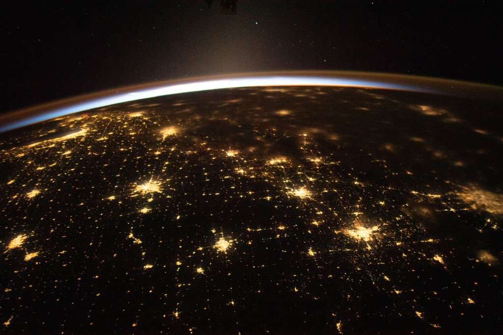 The sun's first rays begin illuminating Earth's atmosphere in this photograph from the International Space Station as it orbited 260 miles above the central United States. At far left, the city lights of Chicago, Illinois, are outlined by Lake Michigan. At far right, the city lights of the Dallas/Forth Worth metropolitan area shine through the clouds.