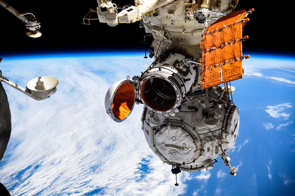 A door is opened on an experiment airlock, attached to to the International Space Station's Nauka science module, that will enable science investigations to be removed, exposed to the external microgravity environment, then returned inside while being maneuvered with the European robotic arm.