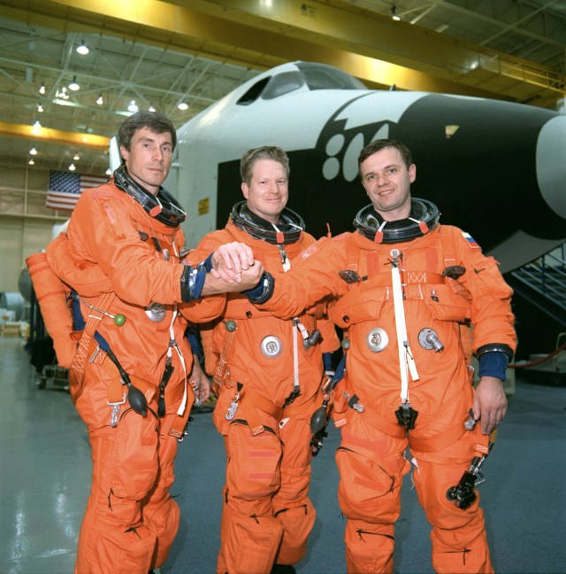 The ISS Expedition 1 crew takes a break from training in the systems integration facility at the Johnson Space Center for a crew photo. From the left are cosmonaut Sergei Krikalev, flight engineer; astronaut William Shepherd, mission commander; and cosmonaut Yuri Gidzenko, Soyuz commander. Behind them is the full fuselage trainer (FFT), one of the full-scale mockups used to prepare the crew for certain phases and contingencies of their shuttle return flight.
