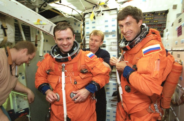 Cosmonaut Yuri Gidzenko (second left), ISS Expedition One Soyuz commander, recruits the aid of astronaut Andrew S.W. Thomas (second right) in putting final touches on his suit-up process as cosmonaut Sergei Krikalev, Expedition One flight engineer, looks on. They are on the mid deck of the crew compartment trainer (CCT) at the Johnson Space Center's Systems Integration Facility. This type training is designed to prepare the crew members for emergency ejection or egress from a shuttle in trouble. The first crew to man the ISS, which includes these two cosmonauts along with U.S. astronaut William Shepherd, mission commander, will use the Space Shuttle Discovery to return to Earth once their expedition tour is complete.