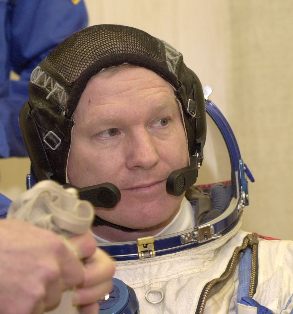 Expedition 1 commander William M. (Bill) Shepherd gets help with his Sokol suit prior to a simulation at Baikonur. Out of frame are Soyuz pilot Yuri P. Gidzenko and flight engineer Sergei K. Krikalev.