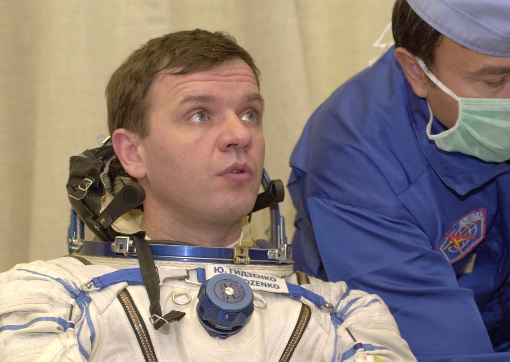 Expedition 1 Soyuz commander Yuri P. Gidzenko, wearing a Sokol suit, gets help with his suit before entering the Soyuz spacecraft at Baikonur. Out of frame are Expedition 1 commander William M. (Bill) Shepherd and flight engineer Sergei K. Krikalev.