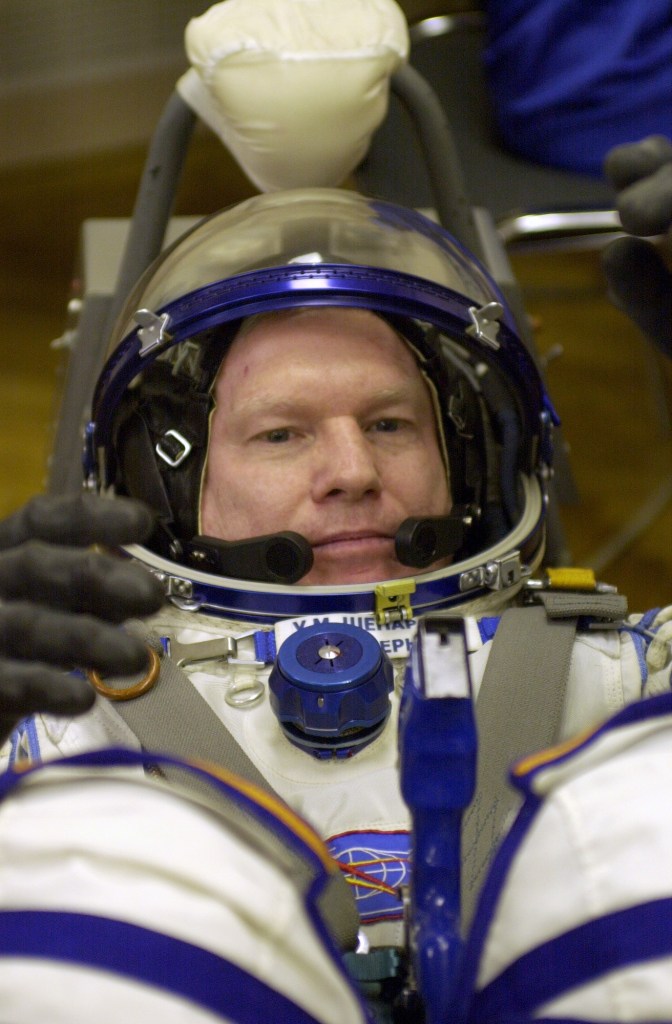 Expedition 1 commander William M. (Bill) Shepherd, wearing a Sokol suit, secures his helmet during a suit-up "dry run" at Baikonur. Out of frame are Soyuz commander Yuri P. Gidzenko and flight engineer Sergei K. Krikalev.