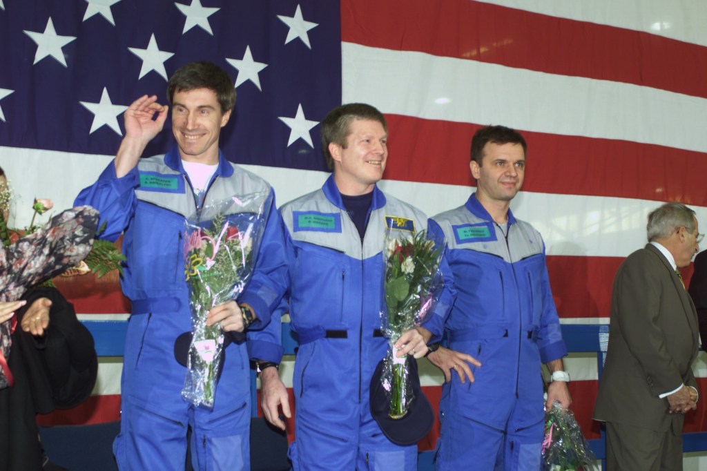 Astronaut William M. (Bill) Shepherd (center), Expedition One mission commander, is flanked by his two cosmonaut crewmates as they greet a crowd gathered for a crew return ceremony in Ellington Field's Hangar 990. Yuri P. Gidzenko (right foreground) served as Soyuz commander for the first staffing of the International Space Station (ISS) and Sergei K. Krikalev (left) was flight engineer.