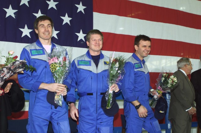 Astronaut William M. (Bill) Shepherd (center), Expedition One mission commander, is flanked by his two cosmonaut crewmates as they greet a crowd gathered for a crew return ceremony in Ellington Field's Hangar 990. Yuri P. Gidzenko (right foreground) served as Soyuz commander for the first staffing of the International Space Station (ISS) and Sergei K. Krikalev (left) was flight engineer.